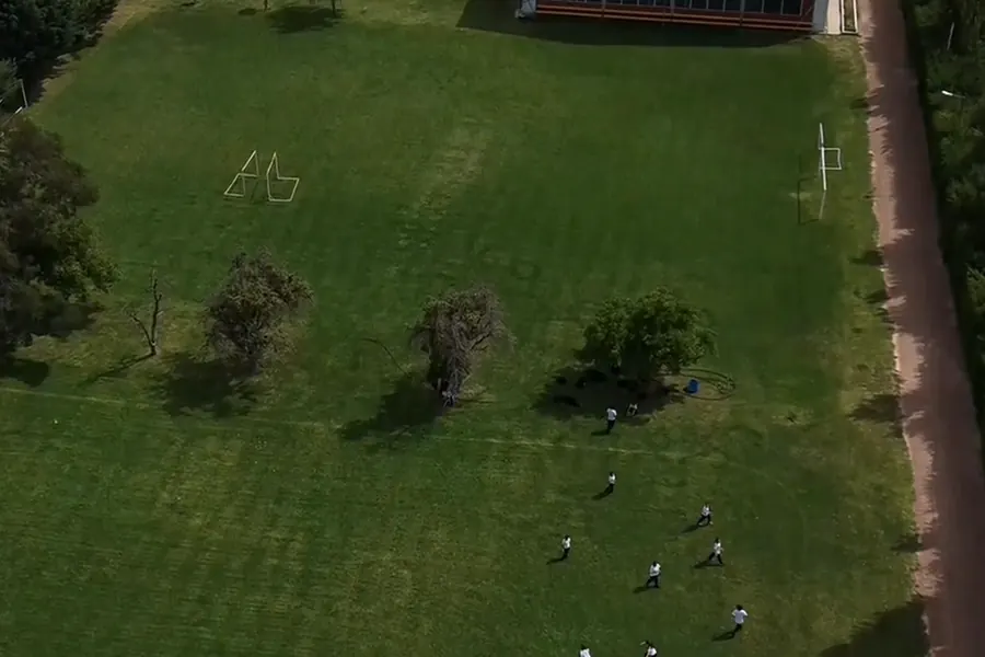 Vista aérea de la cancha de césped del campus, con estudiantes jugando